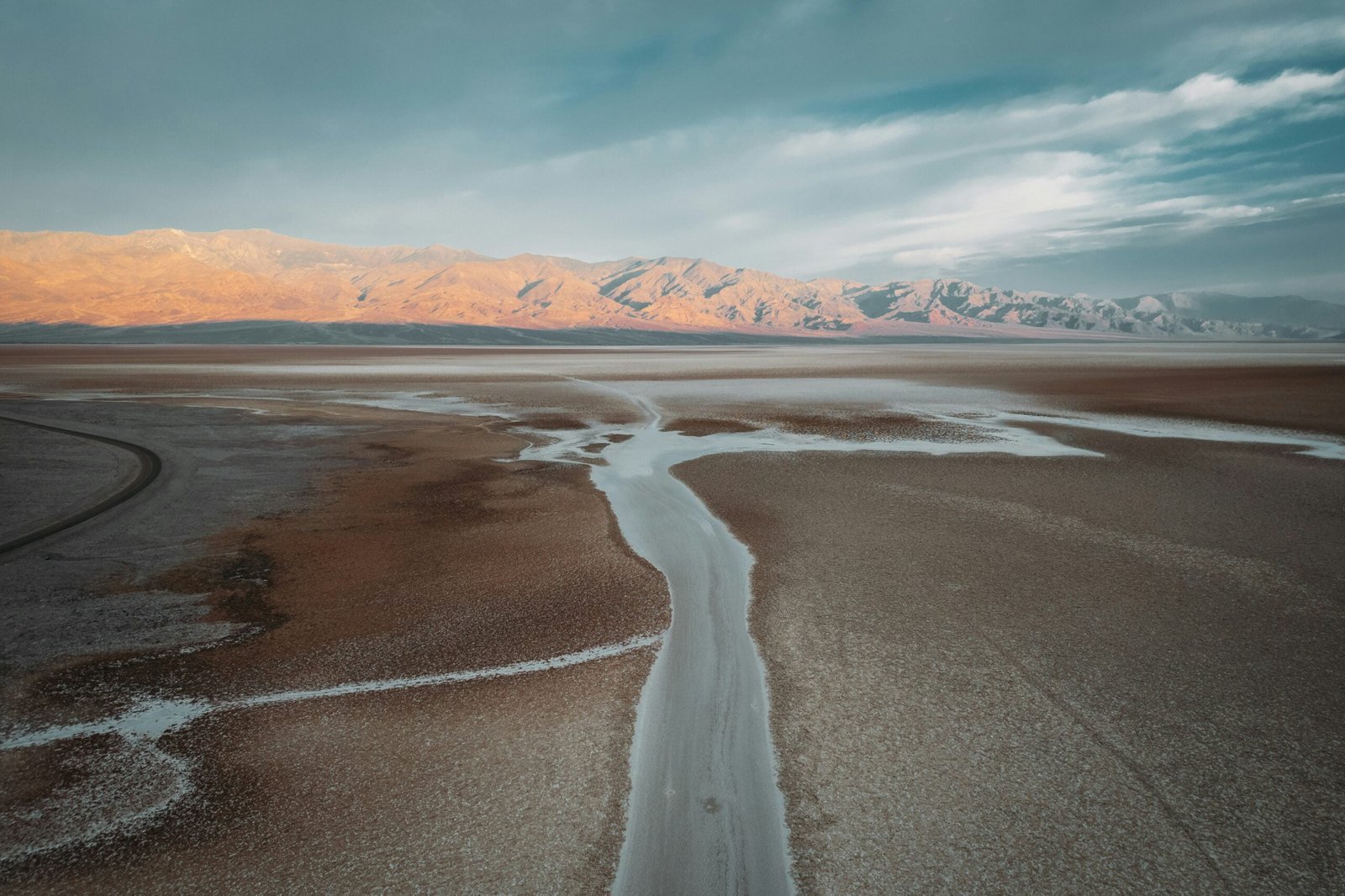 brown and white mountains near body of water under blue sky during daytime